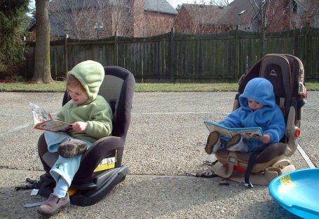 kids reading in their car seats on the driveway